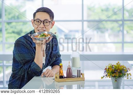 Young Man Wearing Glasses Holding The Fried Egg Served On A Pan With Colorful Toppings Served On A P