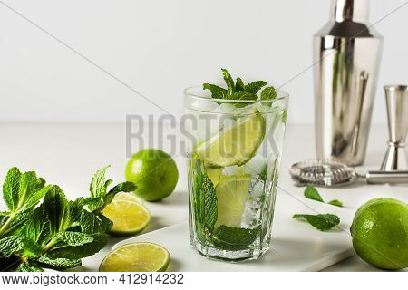 A Glass Of Refreshing Summer Mojito Cocktail With Ice Cubes, Fresh Mint And Lime On White. Ingredien