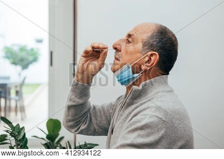 Senior Man Sitting, Self Test For Covid-19 At Home With Antigen Test Kit. Coronavirus Nasal Swab Tes