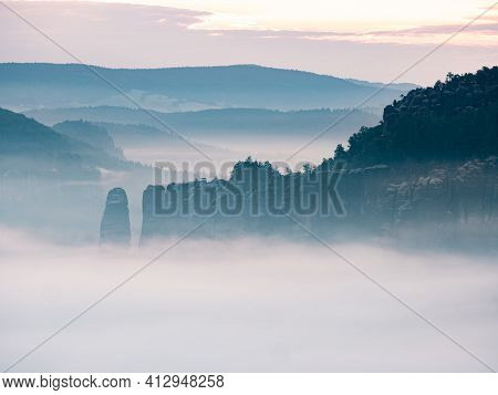 Exposed Rocks And Forest Hills Within Early Morning Hours With Fog. Sachsen Natural Park.  Cold Blue