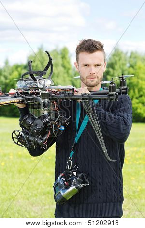 Portrait of confident male engineer holding UAV helicopter in park
