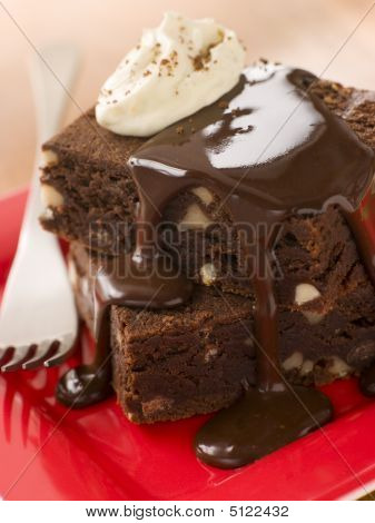 Choklad Brownies på en tallrik med choklad Fudge sås och grädde