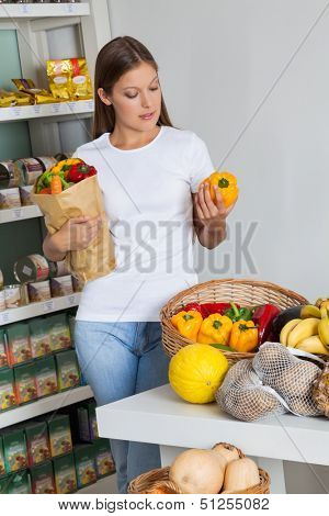 Young woman shopping bellpeppers in supermarket