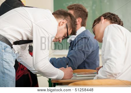 Student in a schoolroom writing in a copybook while his colleague watches