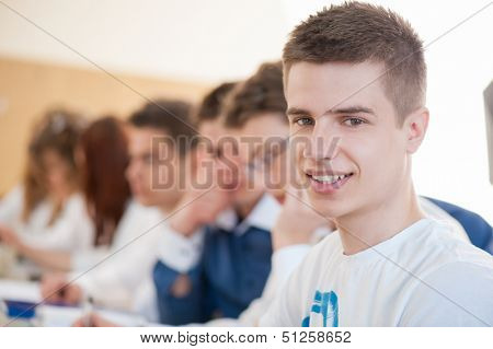 Smiling male student sitting in a schoolroom