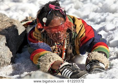 Mt Kailash, Tibet, China - May 26, 2012: Buddhist woman pilgrim making the kora (circumambulation) around Mt. Kailash and performing full body prostrations