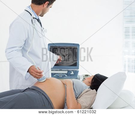 Male doctor performing ultrasound on pregnant woman in clinic