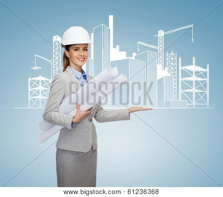 building, developing, consrtuction and architecture concept - smiling architect in helmet with blueprints showing city sketching on palm of hand