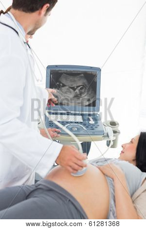 Male doctor showing ultrasound results to pregnant woman in clinic