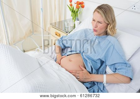 High angle view of expectant woman suffering from labor pains in hospital ward