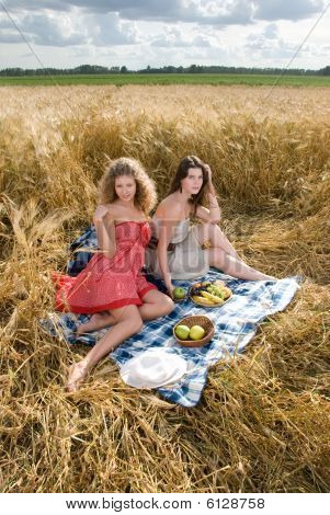 Twol Slavische meisjes op picknick in tarweveld