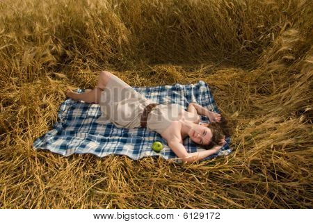 Hermosa chica en el picnic en el campo de trigo con apple