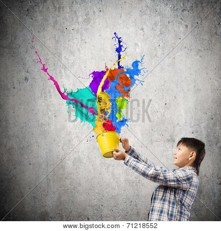 Young boy splashing colorful paint from bucket