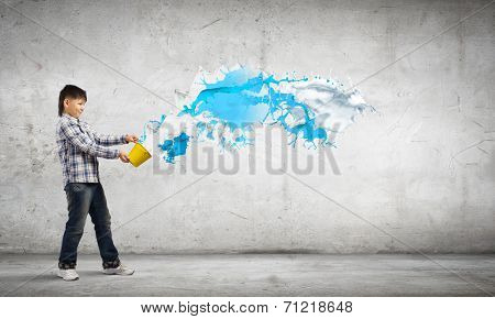 Young boy splashing colorful paint from bucket