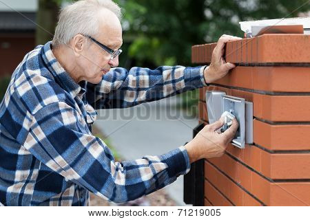 Man Repairing Intercom At The Gate