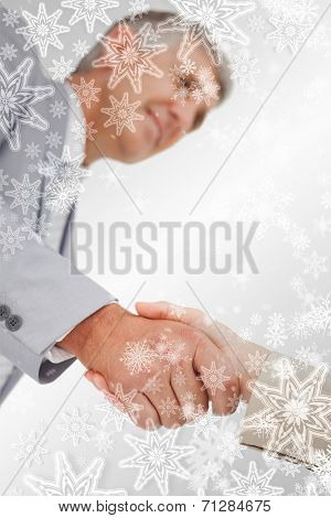 Low angleshot of a hand shake against snowflakes on silver