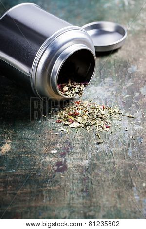 Metal jar with herbal tea on wooden table 