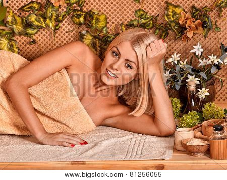 Woman getting back massage in tropical spa. Lying on beige terrycloth