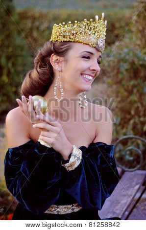 Smiling Young Woman Dressed Like Queen Holding An Apple