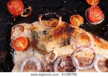 Dish of Pangasius fillet with onion and cherry tomatoes on burn pan background