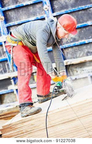 builder carpenter worker with disk saw cutting plywood for falsework construction before concreting at building site