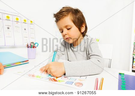 Small boy draws with pencil on the paper sitting