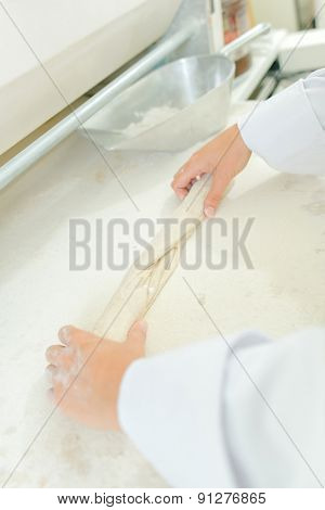 Hands rolling dough