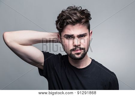 Young handsome man doubting on gray background