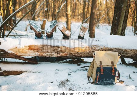 Couple Laying On The Ground In Winter Forest With Legs On The Tree
