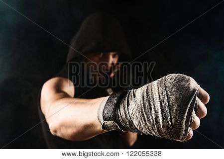 Close-up hand with bandage of muscular man training kickboxing  on black