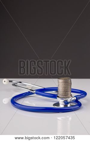 Stethoscope with a stack of coins with a black background