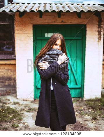 Beautiful woman iwith grey scarf posing near old building