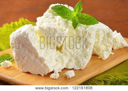 pile of crumbly white cheese on wooden cutting board - close up