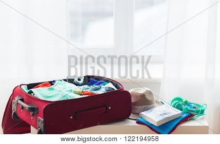 summer vacation, travel, tourism and objects concept - close up of travel bag with clothes and stuff