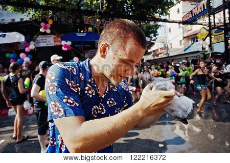 KO SAMUI, THAILAND - APRIL 13: Unidentified photographer smeared with red paint in a water fight festival or Songkran Festival (Thai New Year) on April 13, 2014 in Chaweng Main Road, Ko Samui island, Thailand.