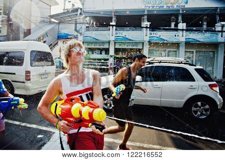KO SAMUI, THAILAND - APRIL 13: Unidentified man shooting water at other people in a water fight festival or Songkran Festival (Thai New Year) on April 13, 2014 in Chaweng Main Road, Ko Samui island, Thailand.
