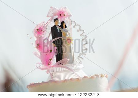 Doll weds of the bride and groom on a wedding cake that symbolizes the commitment to love one another.