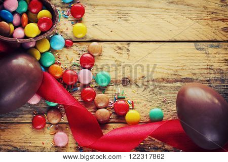 Easter chocolate eggs candy red ribbon on wooden table