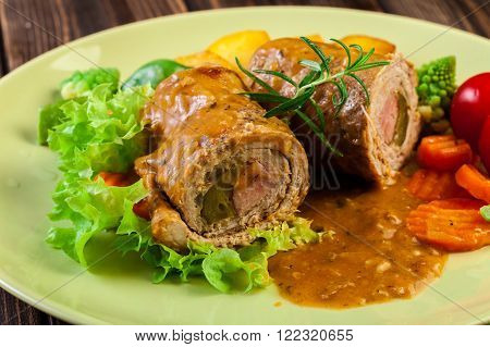 Pork rolls with prepared potatoes and vegetables on plate