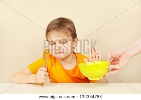 Little cute boy refuses to eat a porridge