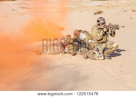 Squad of soldier evacuate the injured fellow in arms hiding in the smoke