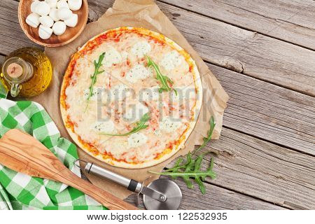 Quattro fromaggi pizza with lettuce on wooden table. Top view with copy space