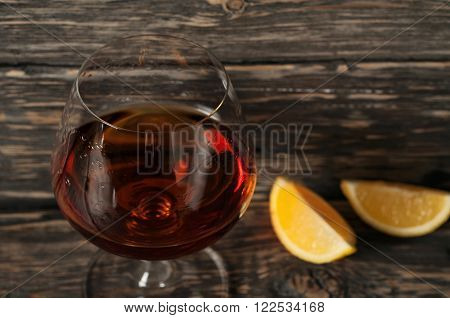 brandy in large round glass on the old wooden background close up. Top view with copy space