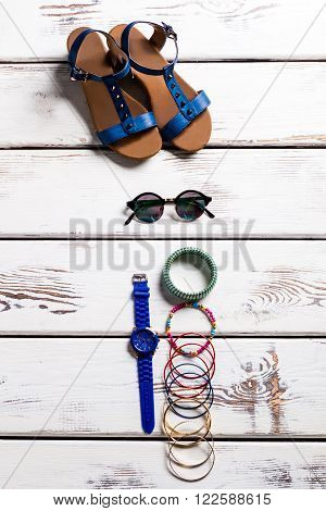 Female sandals and small accessories. Footwear and accessories on shelf. Woman's shoes for summer. Tiny good-looking accessories.