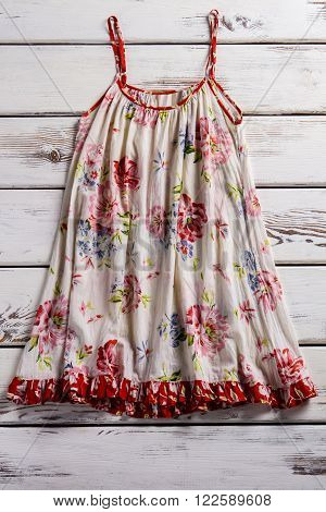 Flax sarafan with thin straps. Vintage sarafan on wooden table. Floral pattern sarafan. Flower pattern garment on showcase.