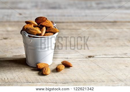Roasted grains of peanuts in a wooden bucket isolated on white background, tasty food
