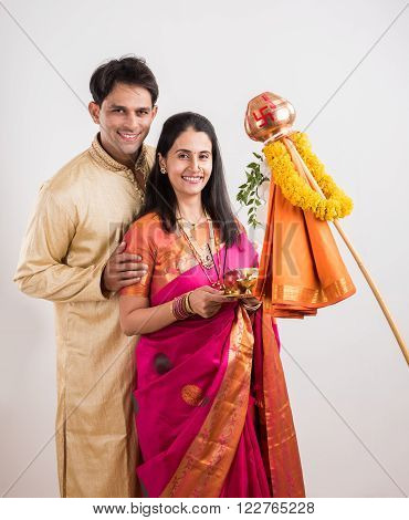 smart indian couple in traditional wear performing gudhi padwa puja, asian couple & puja thali, indian young couple with puja or pooja thali, hindu new year gudhi / gudi padwa, isolated on white