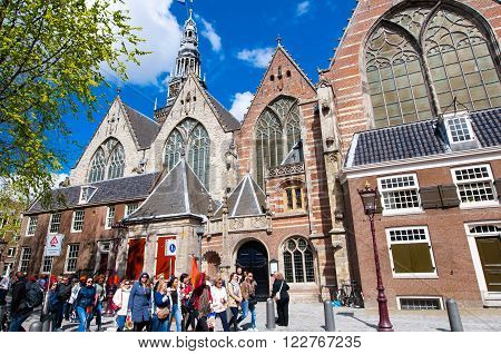 Amsterdam-April 27: Oude Kerk in Amsterdam's red-light district tourists go sightseeing on April 272015 the Netherlands. The Oude Kerk is Amsterdam's oldest parish church consecrated in 1306.