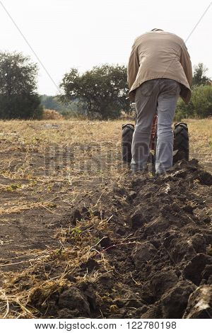 DIKANKA UKRAINE - SEPTEMBER 30 2015: Country farmer is plowing his garden with walk-behind garden tractorautumn field work