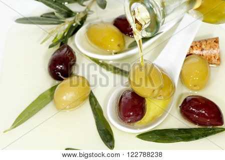 pouring olive oil on green and brown olives